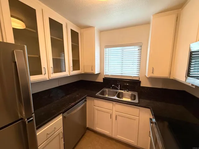 a kitchen with granite countertop white cabinets and black appliances