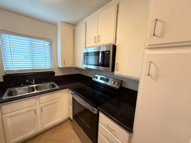 a view of a refrigerator in kitchen and an empty room
