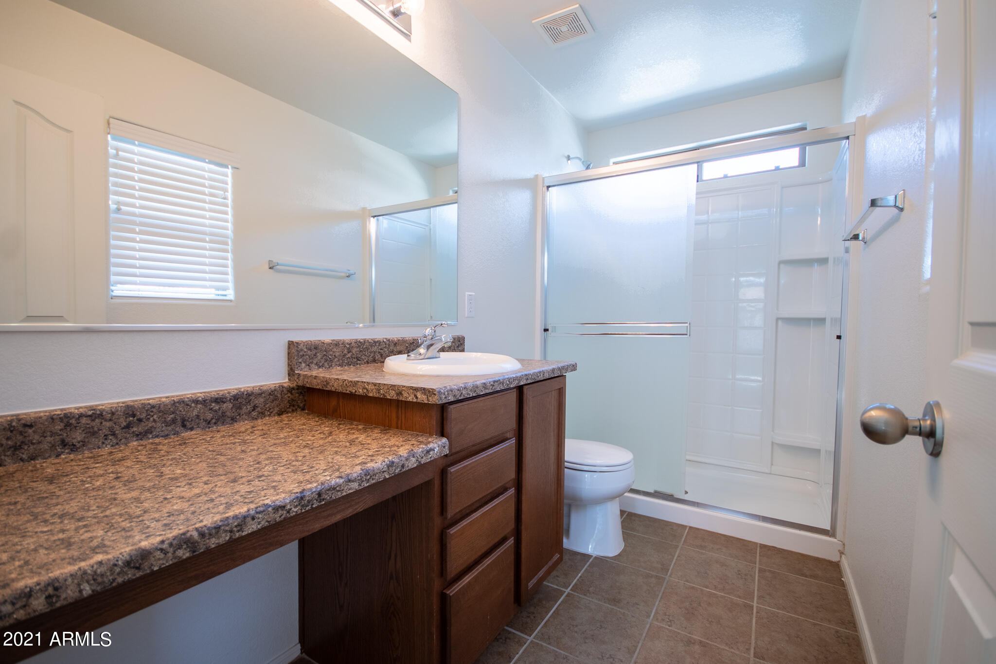 6433 West Harwell Road Laveen, AZ 85339 - Photo 10 of 18 a bathroom with a granite countertop sink a toilet a mirror and shower