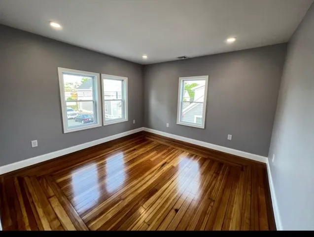a view of empty room with window and wooden floor