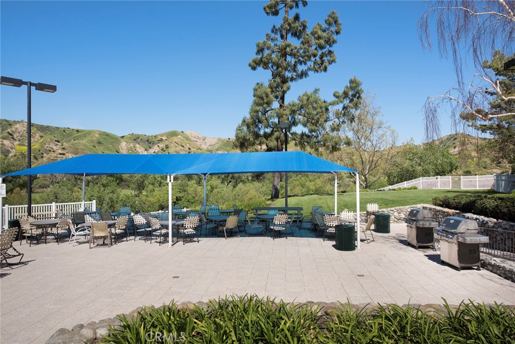 4817 Golden Ridge Drive Corona, CA 92878 - Photo 62 of 70 a view of a patio with a table and chairs under an umbrella with potted plants
