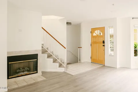 a view of an empty room with wooden floor and a fireplace