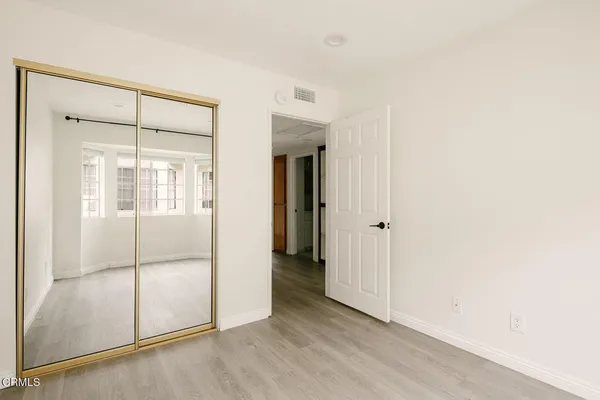 a view of an empty room with wooden floor and closet