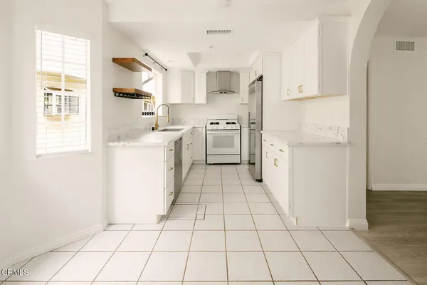 a kitchen with white cabinets a sink and appliances