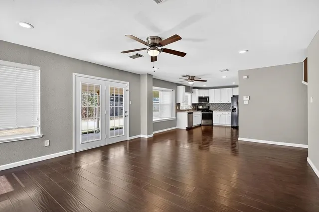 a view of an empty room with wooden floor and a window