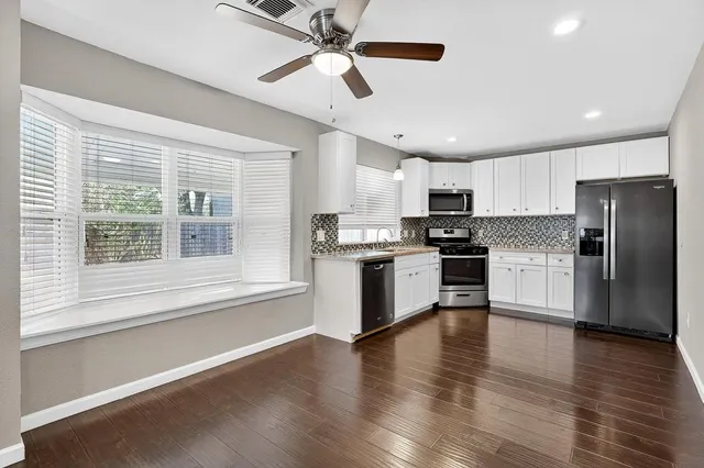 a kitchen with granite countertop stainless steel appliances cabinets and a large window