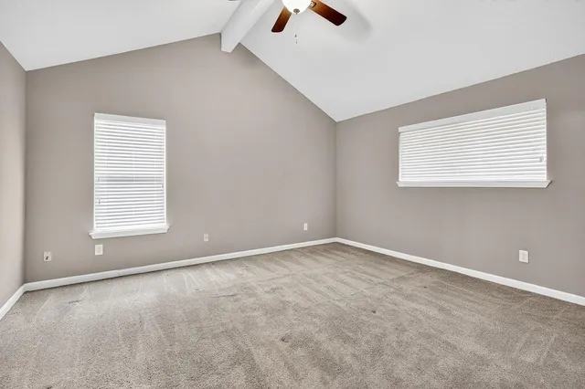 an empty room with ceiling fan and window