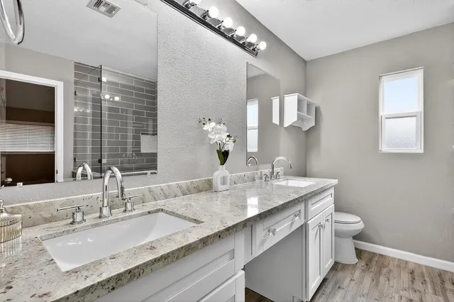 a bathroom with a granite countertop sink a large mirror and a toilet