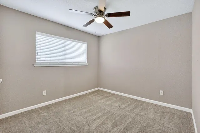 an empty room with a window and a fan