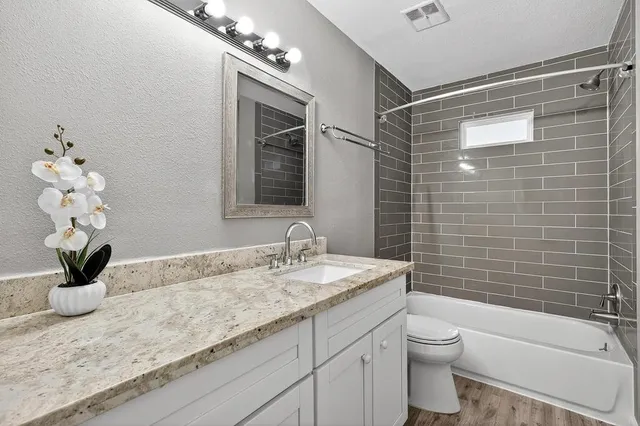 a bathroom with a granite countertop sink a toilet and shower