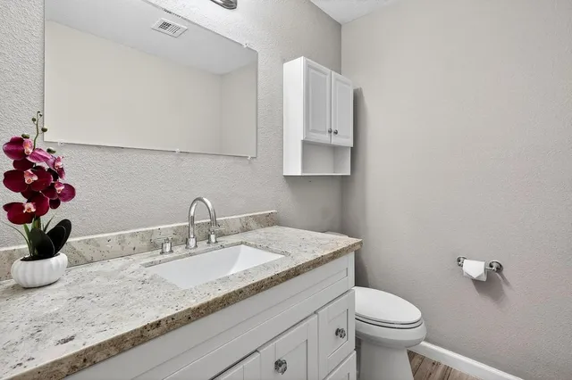 a bathroom with a granite countertop sink a toilet and mirror