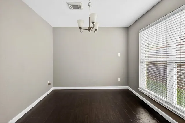 an empty room with wooden floor windows and chandelier