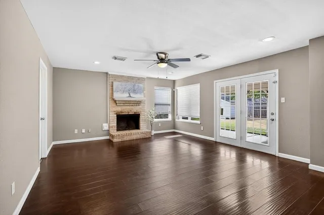 a view of an empty room with window and wooden floor