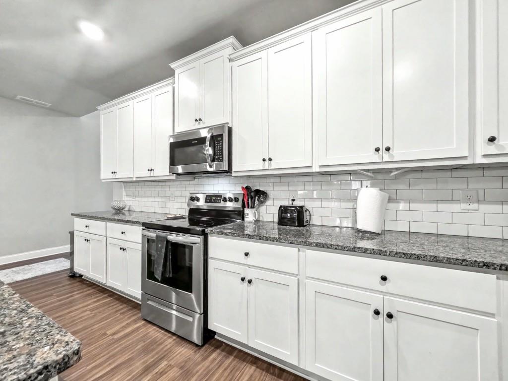 453 Mulberry Rock Road Temple, GA 30179 - Photo 12 of 35 a kitchen with granite countertop white cabinets and white stainless steel appliances