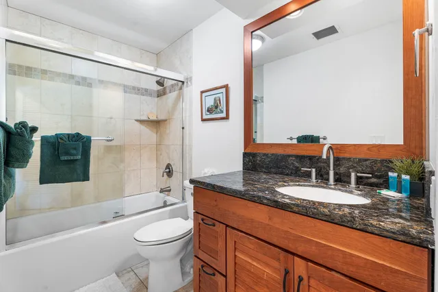 a bathroom with a granite countertop sink toilet and shower