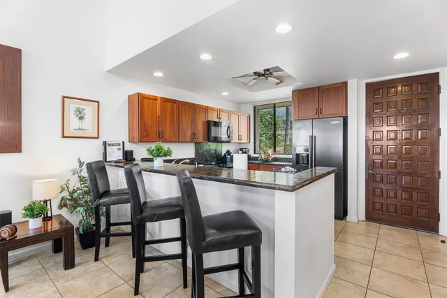 a kitchen with granite countertop a table chairs microwave and refrigerator