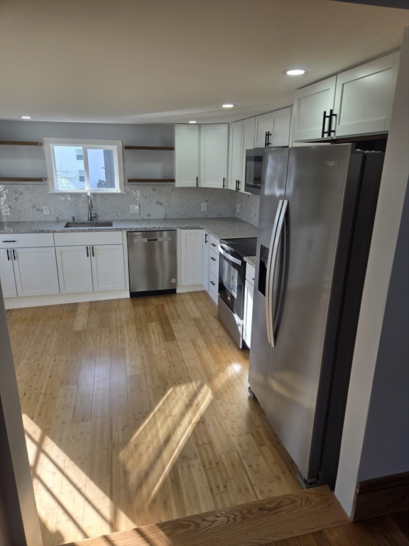 22 Linden Street Reading, MA 01867 - Photo 5 of 32 a kitchen with granite countertop a refrigerator a sink a stove a microwave and island