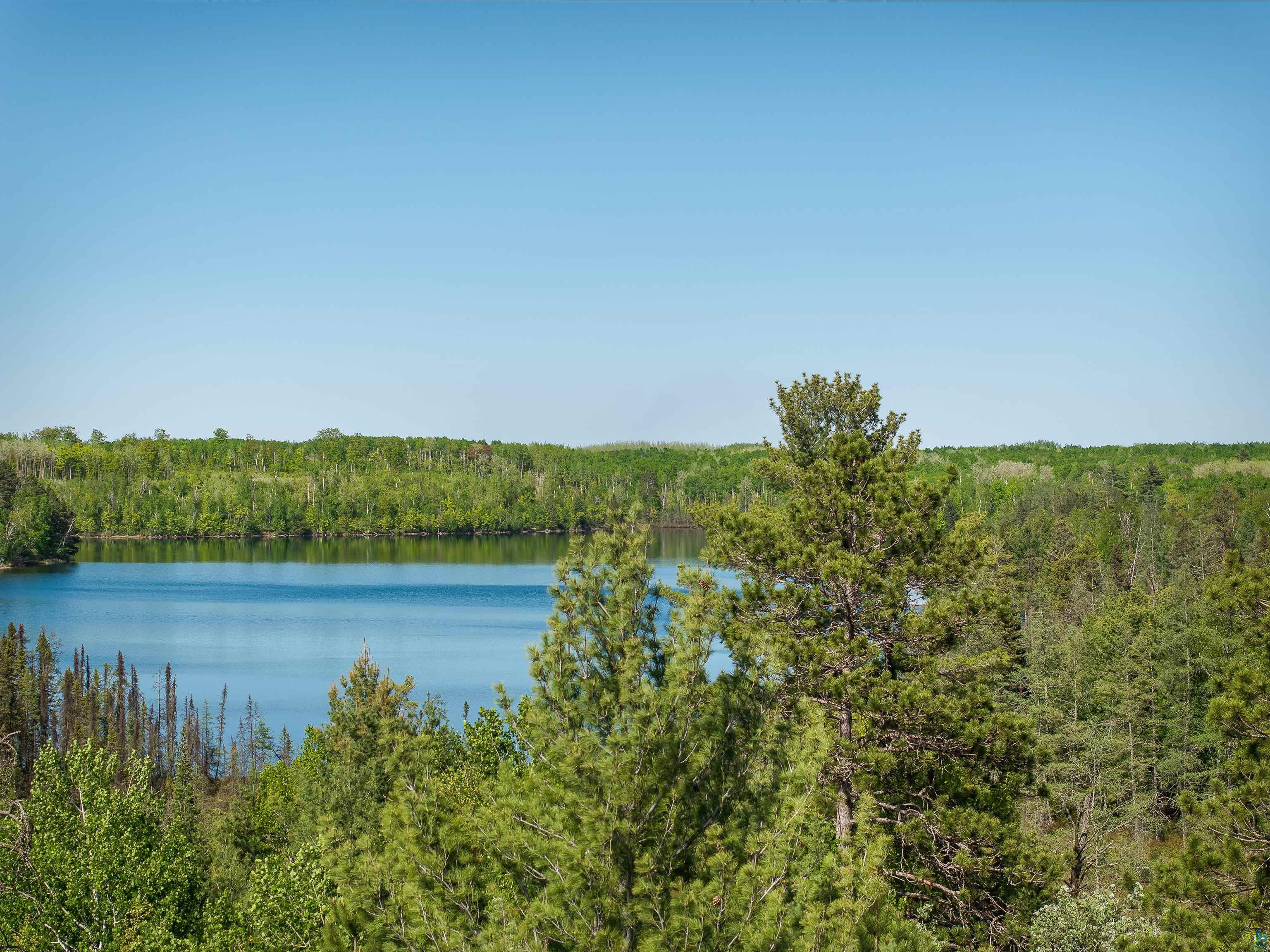 9064 Peppard Road Britt, MN 55710 - Photo 31 of 40 Expansive natural landscape featuring a prominent blue body of water surrounded by dense evergreen and deciduous trees under a clear sky