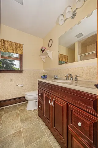 a spacious bathroom with a granite countertop sink a toilet and a mirror