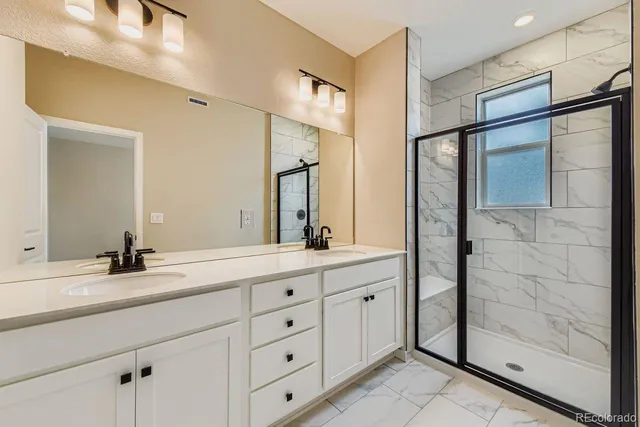a bathroom with a double vanity sink mirror and shower