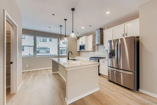 a kitchen with stainless steel appliances a refrigerator a sink and wooden floors