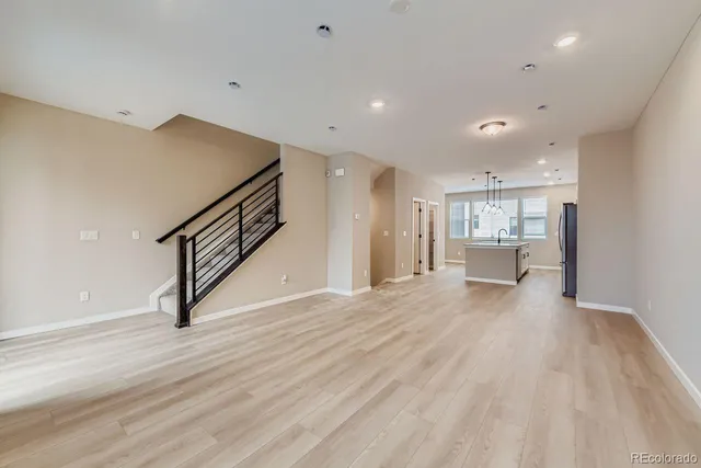 a view of an empty room with wooden floor and a sink