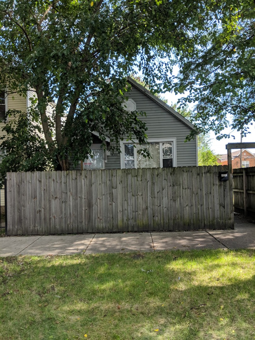 a view of a backyard with a large tree and wooden fence