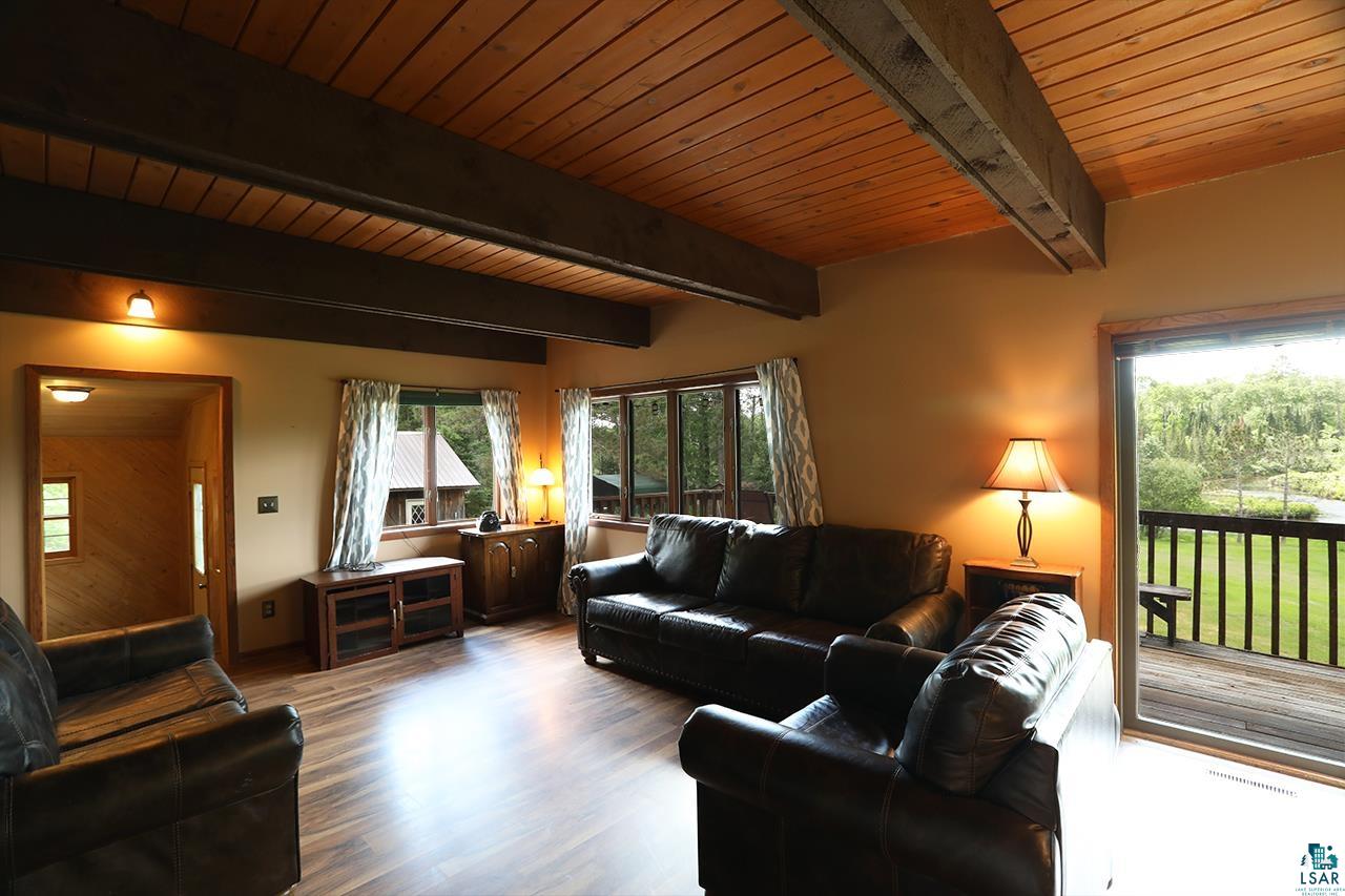 9289 Heino Road Angora, MN 55703 - Photo 6 of 37 Vaulted wood-finish ceiling with exposed beams, wood-finish flooring, multiple windows, and sliding glass door access to an outdoor deck