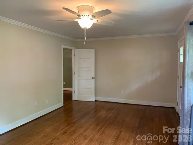 an empty room with wooden floor chandelier fan and closet area