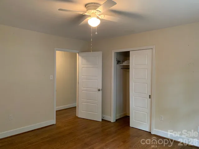 an empty room with wooden floor closet and windows