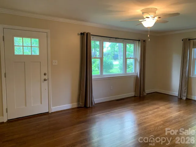 a view of an empty room with wooden floor and a window