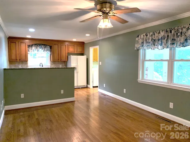 a view of an empty room with window and wooden floor