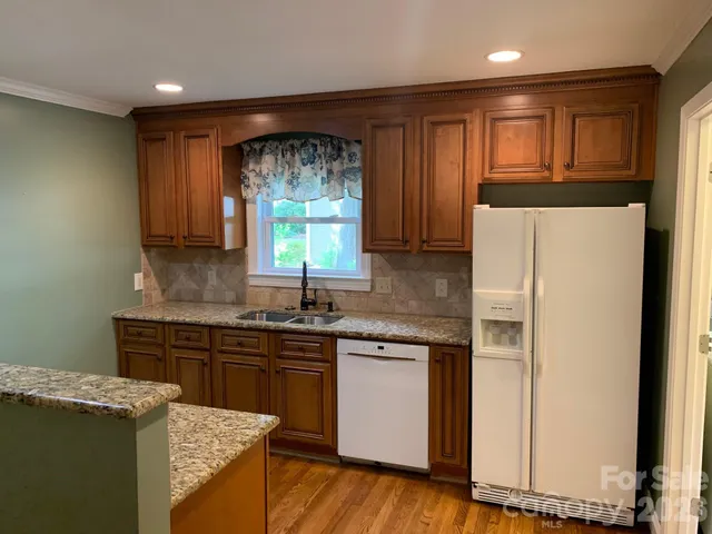 a kitchen with a sink a window a refrigerator and wooden cabinets