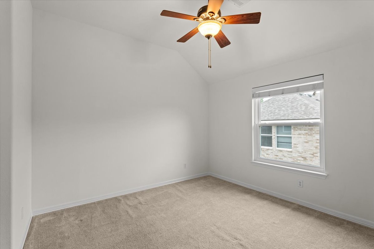 2304 Village View Loop Pflugerville, TX 78660 - Photo 38 of 40 A comfortable bedroom features plush carpeting, a vaulted ceiling, and ample natural light from a well-sized window.