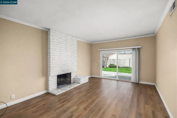 an empty room with wooden floor fireplace and windows