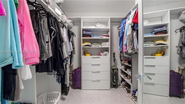 a view of walk in closet with clothes and shoes