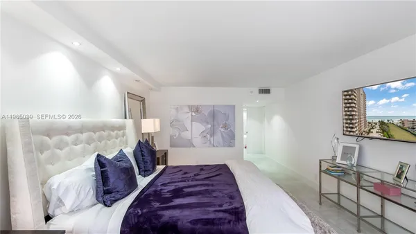 a spacious bedroom with a bed and a flat screen tv