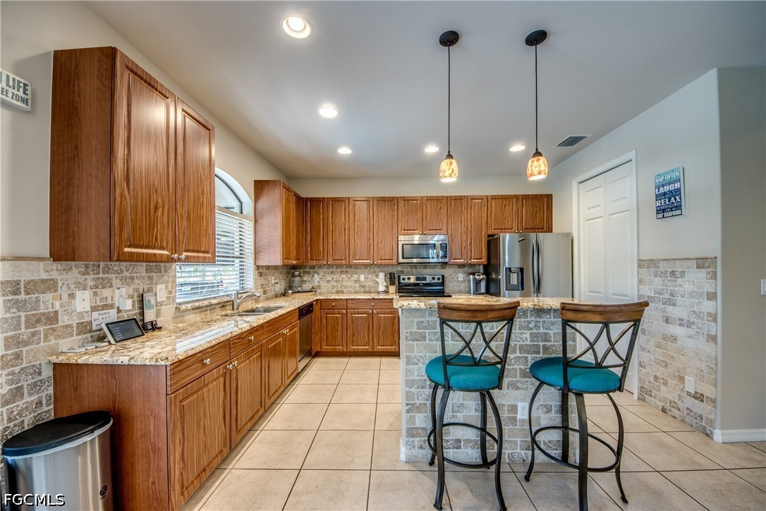 5601 Del Rio Court Cape Coral, FL 33904 - Photo 16 of 50 a kitchen with stainless steel appliances granite countertop a sink a stove a refrigerator a microwave oven with a dining table and chairs