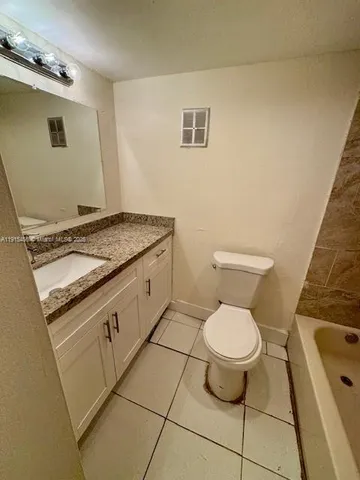 a bathroom with a granite countertop sink a toilet and bathtub