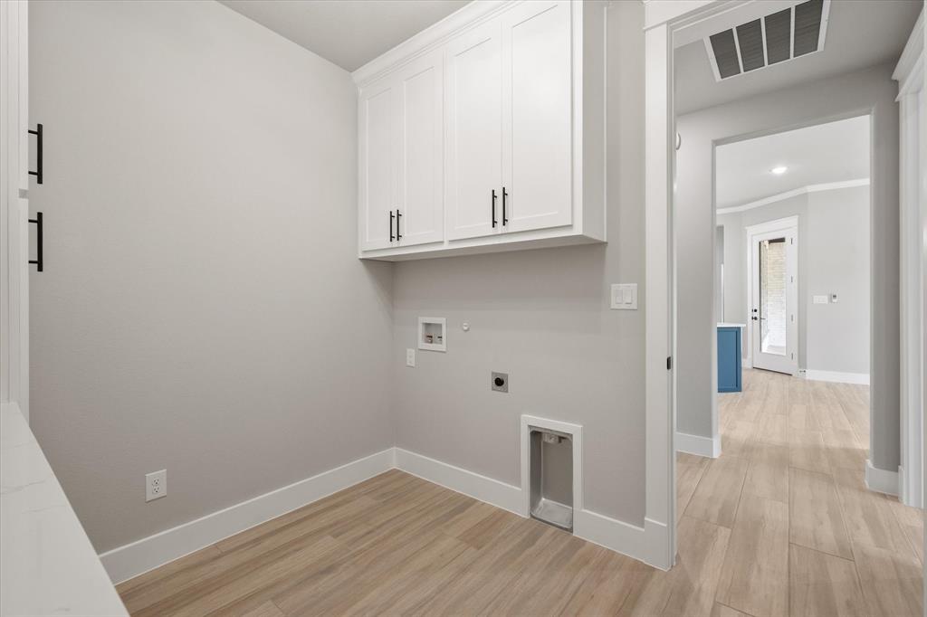 6610 Waggoner Way Midlothian, TX 76065 - Photo 27 of 40 Laundry area featuring white shaker-style cabinetry with black hardware, light wood-finish flooring, and light gray walls