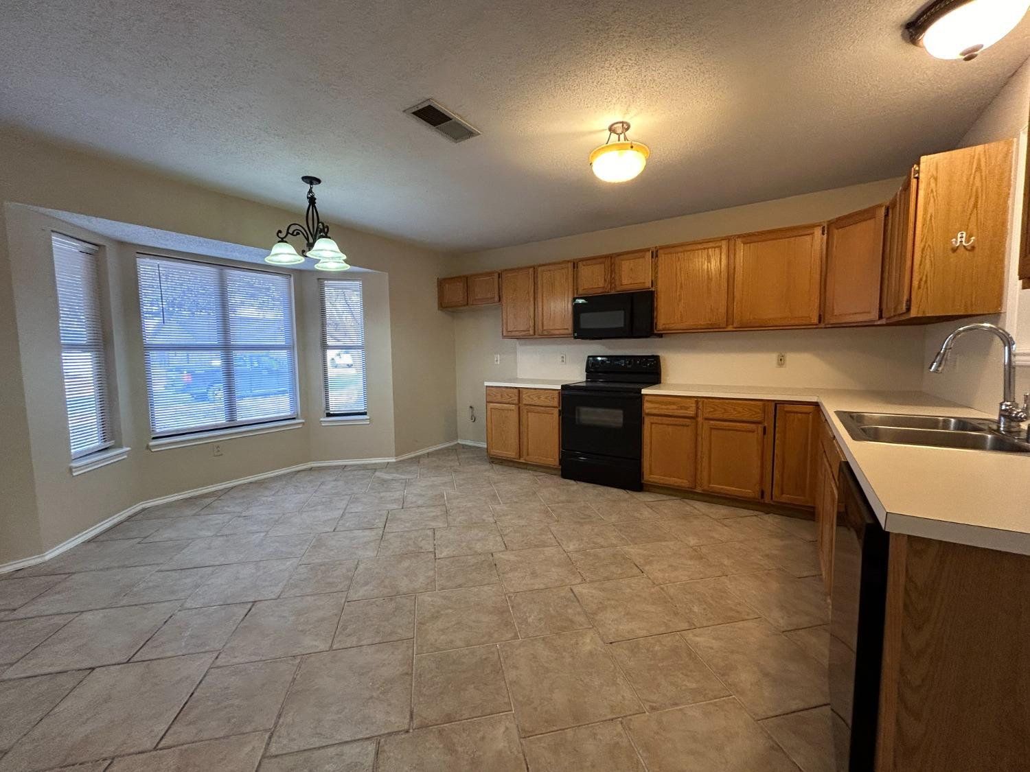 5917 74th Street Lubbock, TX 79424 - Photo 3 of 9 a kitchen with stainless steel appliances granite countertop a sink a stove and a refrigerator