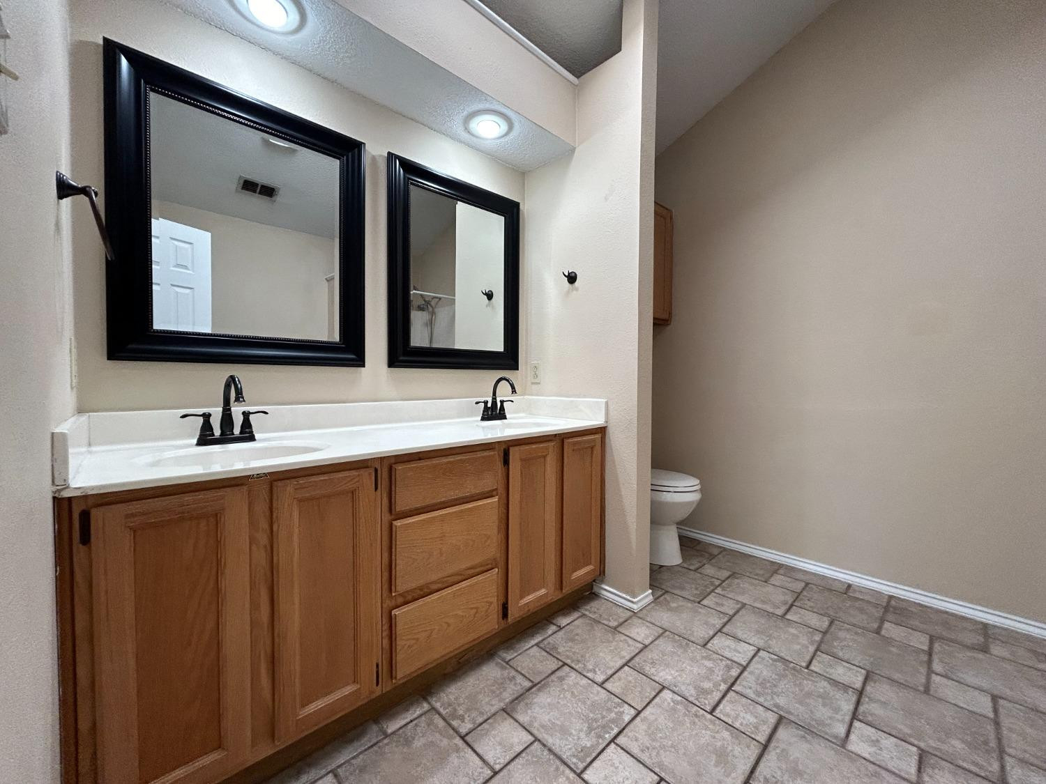 5917 74th Street Lubbock, TX 79424 - Photo 5 of 9 a bathroom with a double vanity sink mirror and toilet