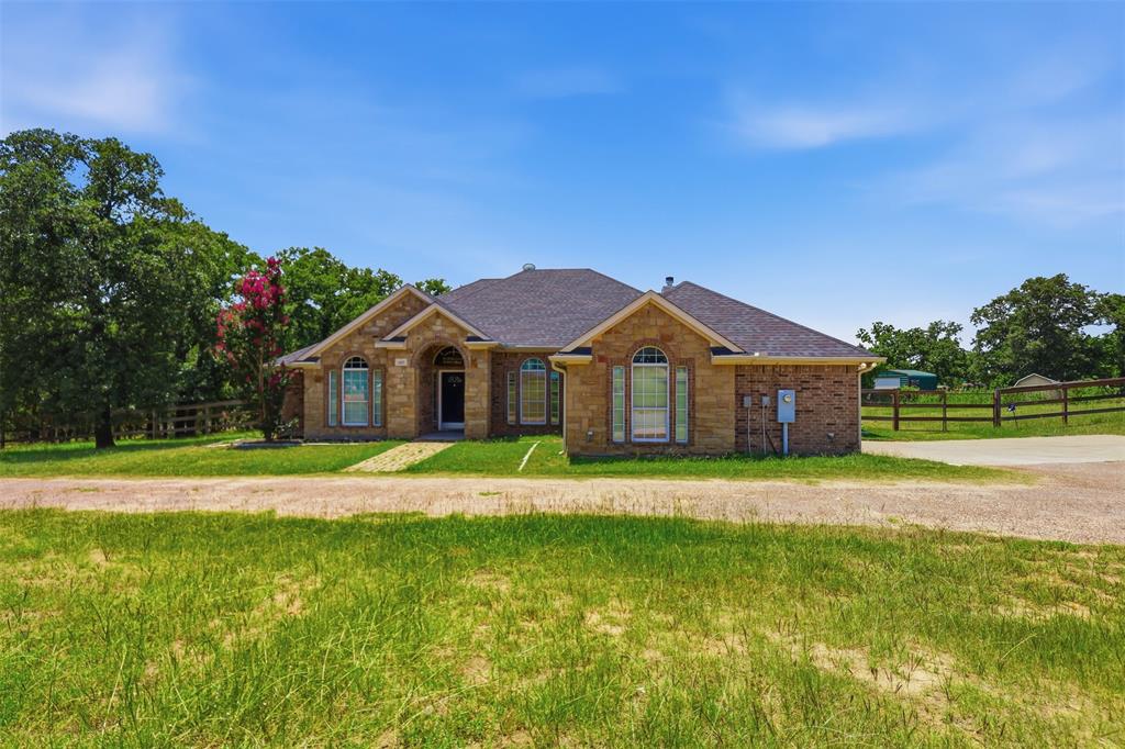 4417 Slayton Road Cleburne, TX 76031 - Photo 1 of 28 Brick and stone exterior residence featuring a dark shingled roof, arched entry, and arched windows with shutters