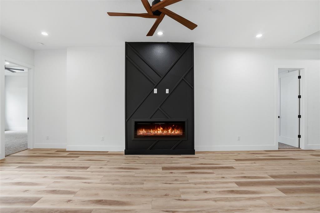 1111 Riverwood Road Dallas, TX 75217 - Photo 19 of 40 Open-concept living space with wood-finish flooring, a contemporary fireplace feature wall, recessed lighting, and a modern ceiling fan