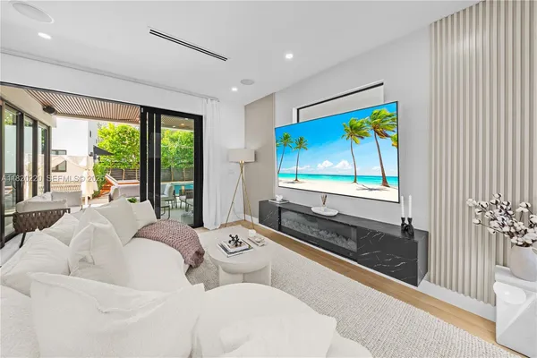 a living room with furniture floor to ceiling window and a flat screen tv