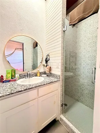 a bathroom with a granite countertop sink mirror and shower