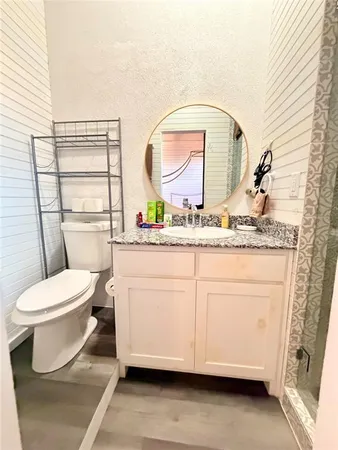a bathroom with a granite countertop toilet sink and mirror
