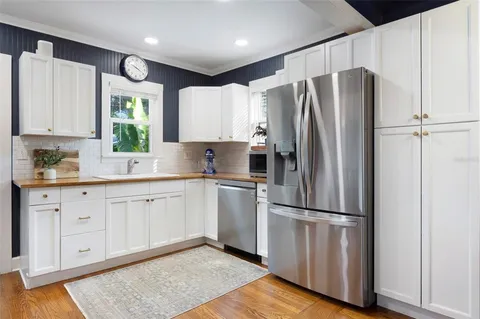 a kitchen with granite countertop stainless steel appliances a refrigerator sink and cabinets