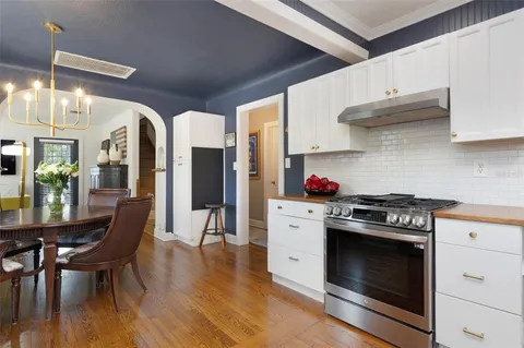 a kitchen with stainless steel appliances granite countertop a stove a refrigerator and a dining table with wooden floors