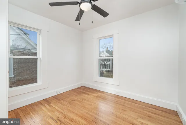 a view of empty room with wooden floor and fan